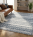 Tapis rectangulaire 180x270 à motifs géométriques bleus et crème dans un salon moderne avec parquet en chevrons